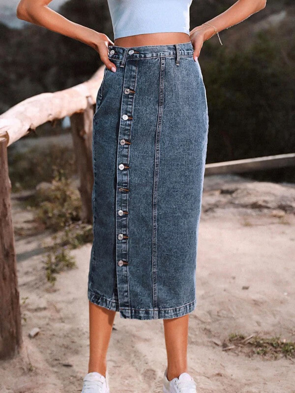 Woman wearing a high-waisted denim midi skirt with a button-front and side slit outdoors.