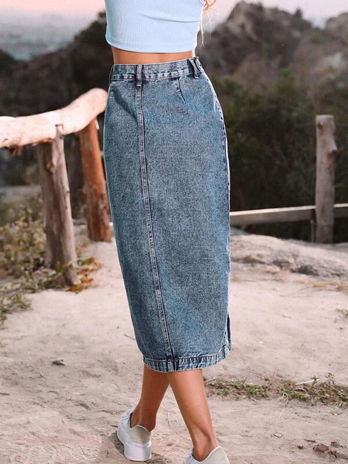 Woman wearing a high-waisted denim midi skirt with a button-front and side slit outdoors.