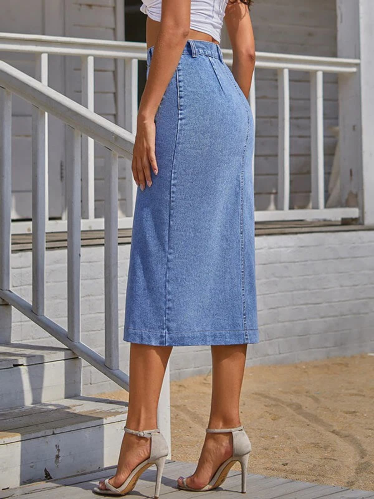 Woman wearing a high-waisted denim midi skirt with a button-front and side slit outdoors.