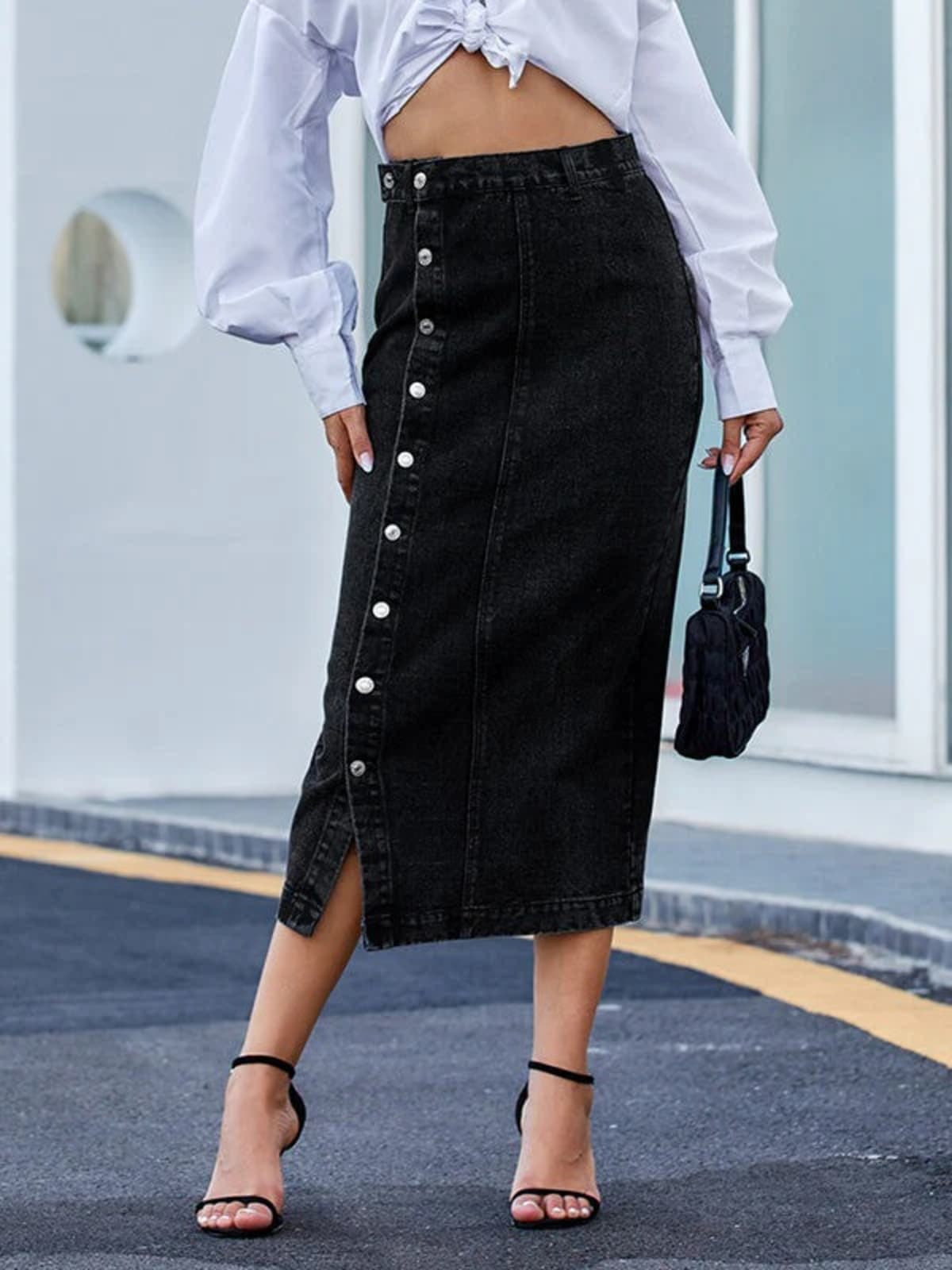 Woman wearing a high-waisted denim midi skirt with a button-front and side slit outdoors.