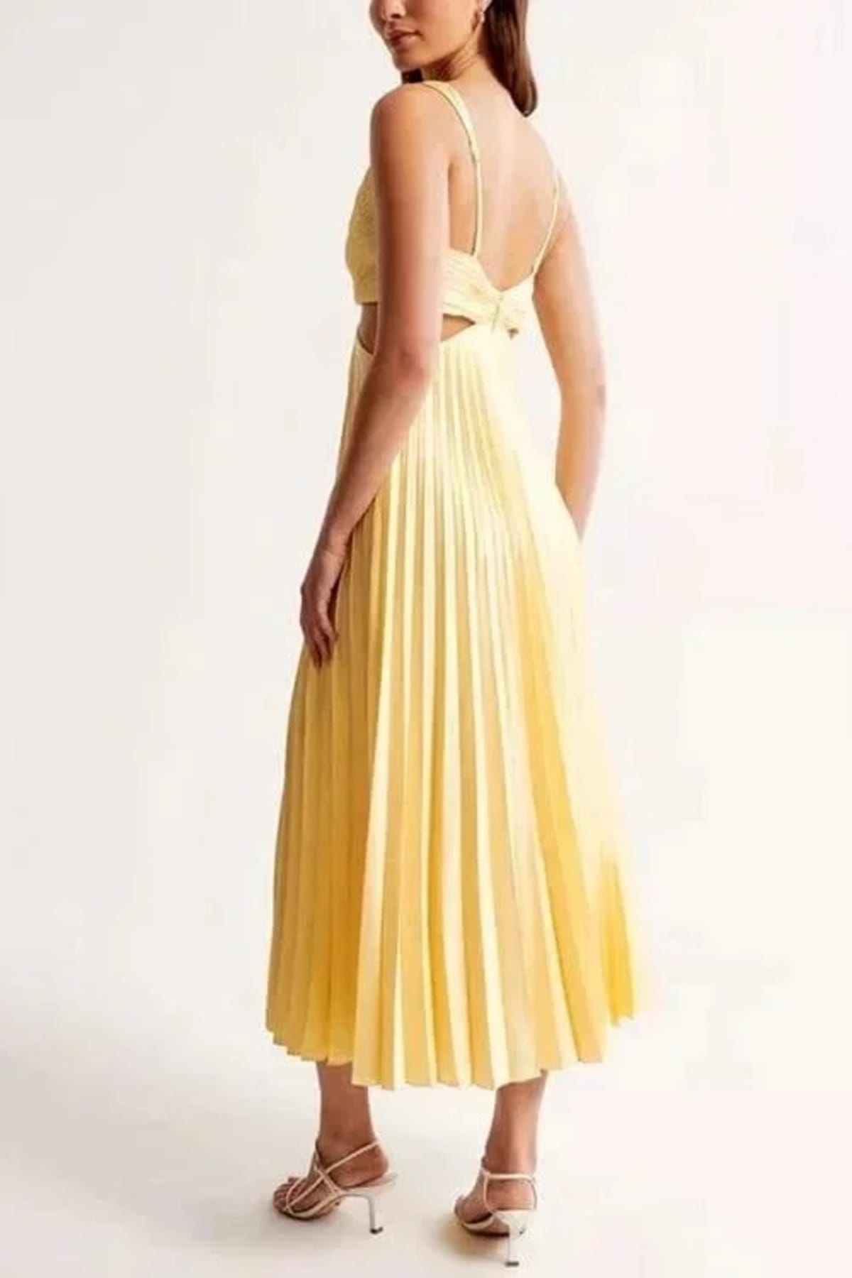 Model wears pleated midi dress with V-neck and side cut-outs.