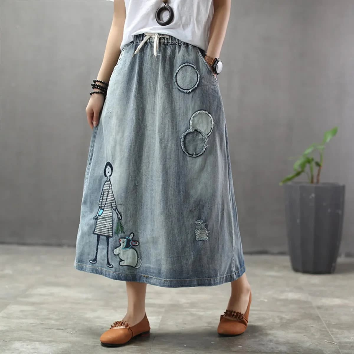 Woman wearing a denim maxi skirt with embroidery and patches