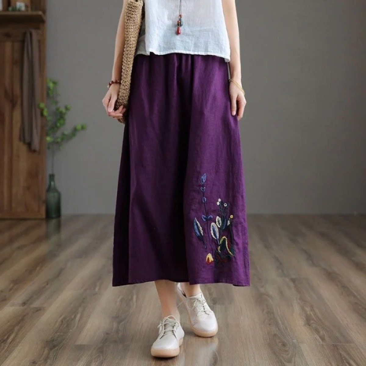 Person wears a loose-fitting midi skirt with floral embroidery.