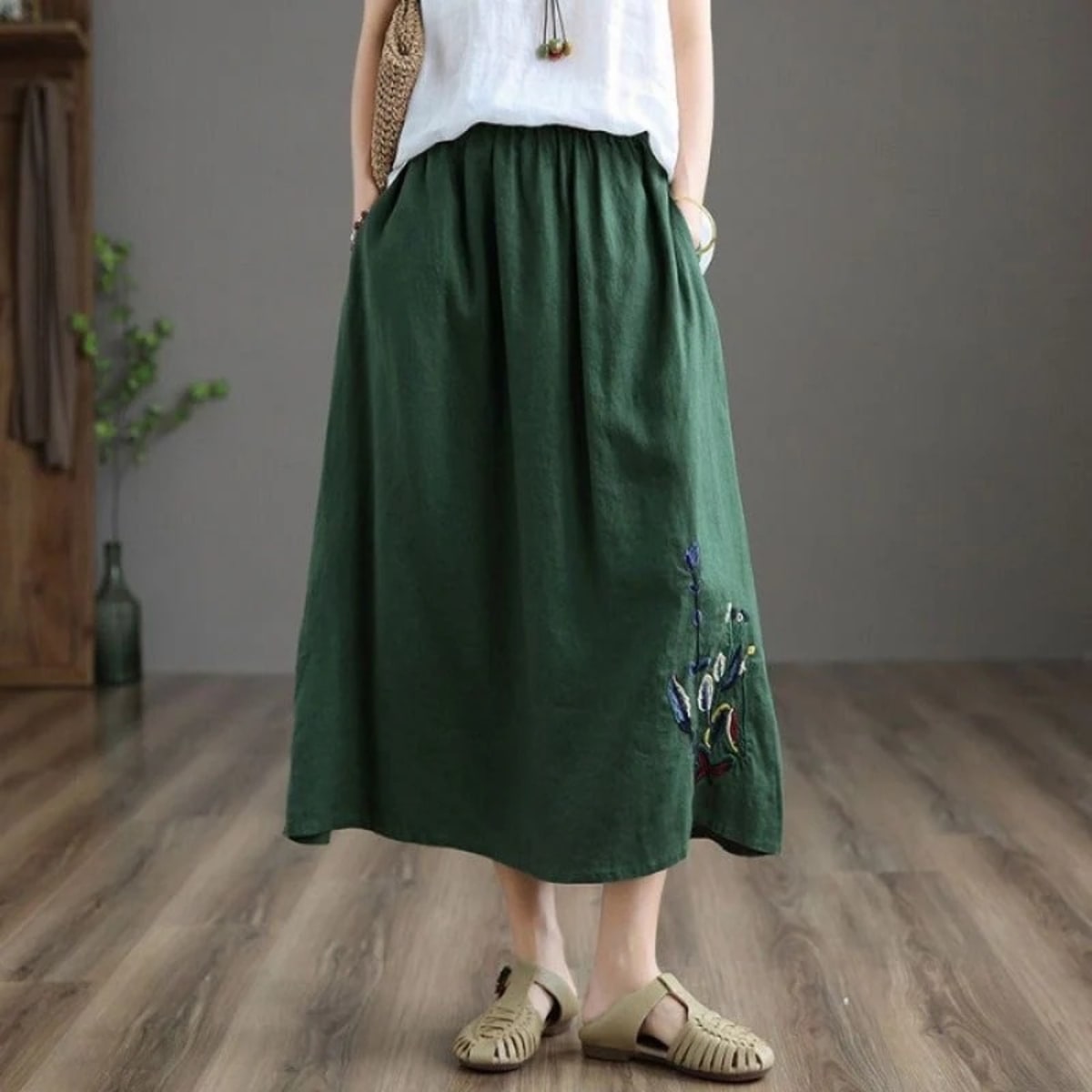 Person wears a loose-fitting midi skirt with floral embroidery.