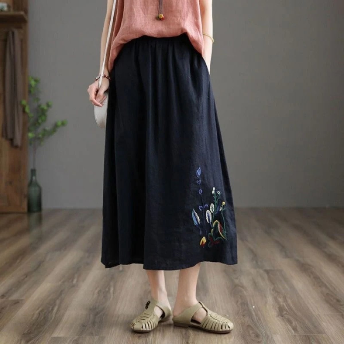 Person wears a loose-fitting midi skirt with floral embroidery.