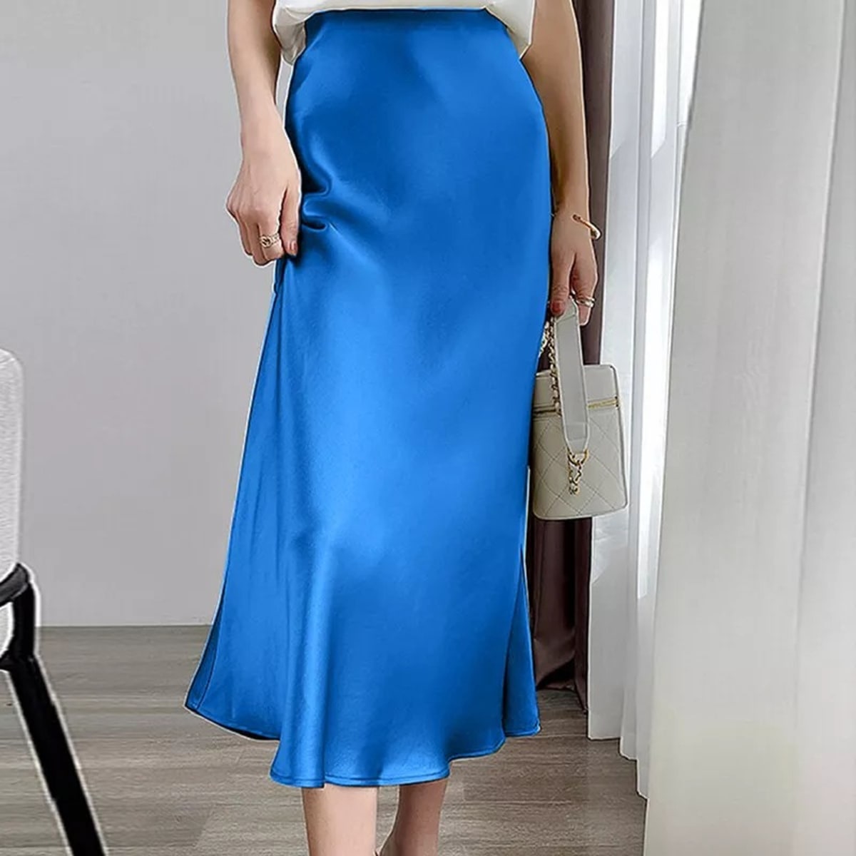 Woman wearing a high-waisted flowy midi slip skirt.