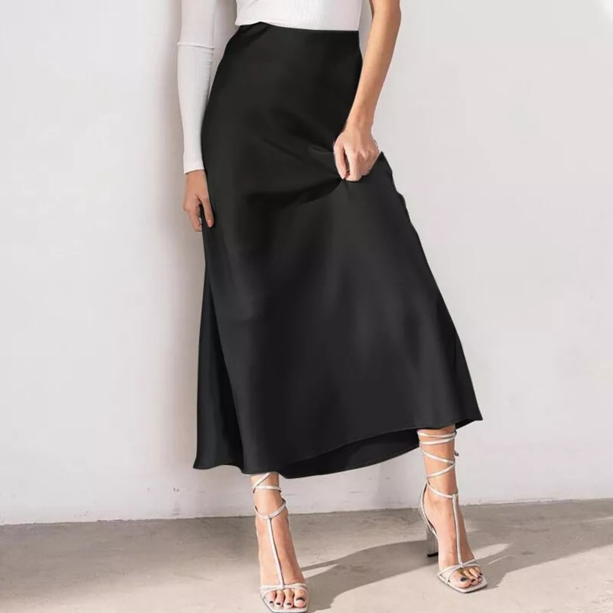 Woman wearing a high-waisted flowy midi slip skirt.