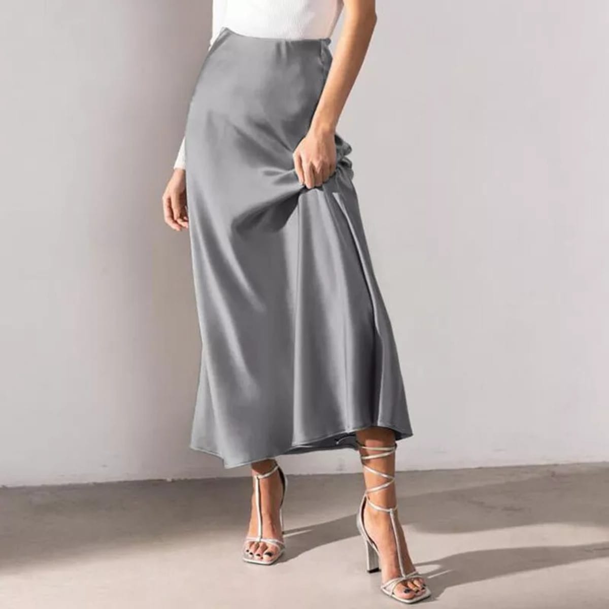 Woman wearing a high-waisted flowy midi slip skirt.