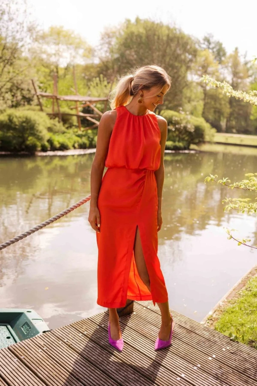 Woman in halter neck midi dress with slit on a dock.