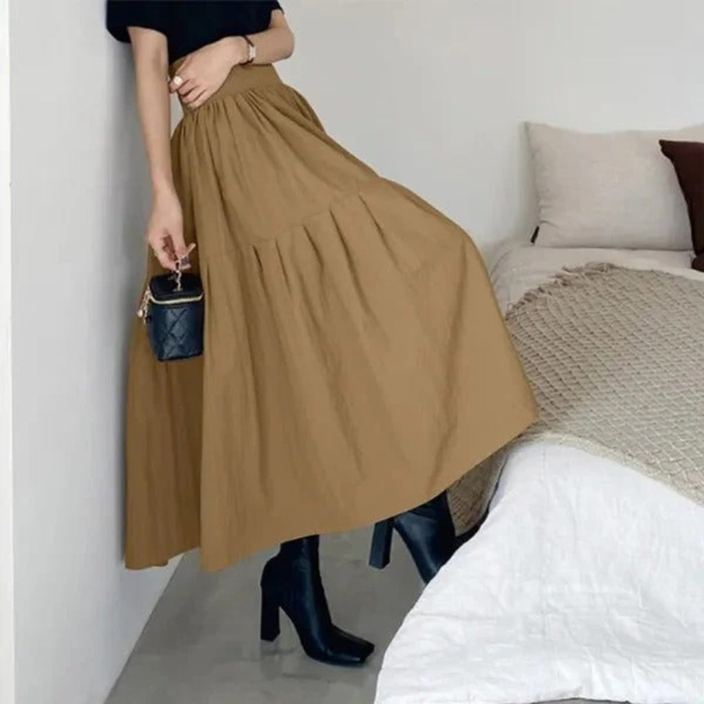 Woman wearing high-waisted pleated tiered midi skirt with black top.