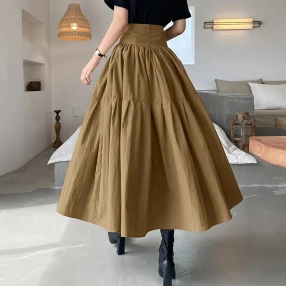 Woman wearing high-waisted pleated tiered midi skirt with black top.
