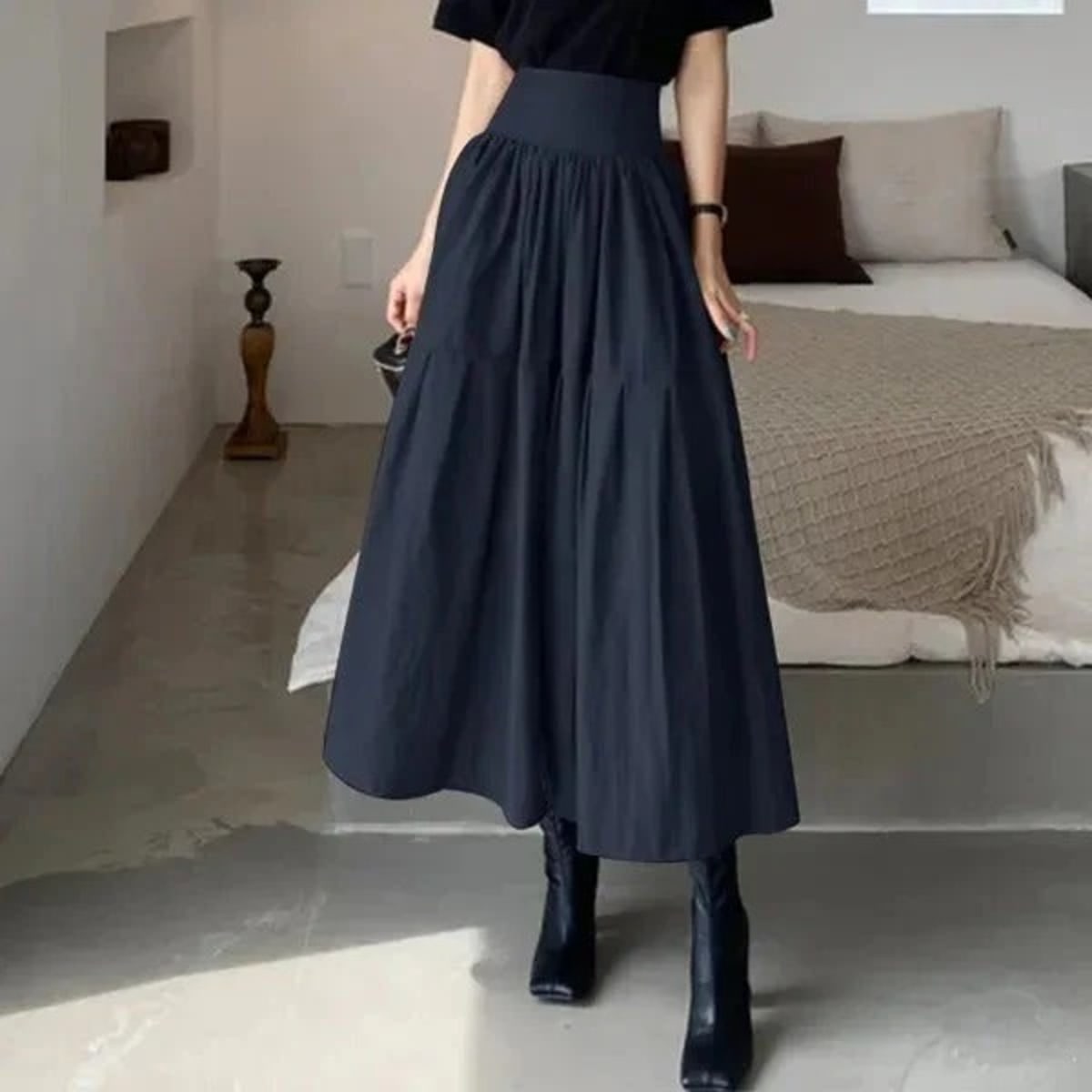 Woman wearing high-waisted pleated tiered midi skirt with black top.