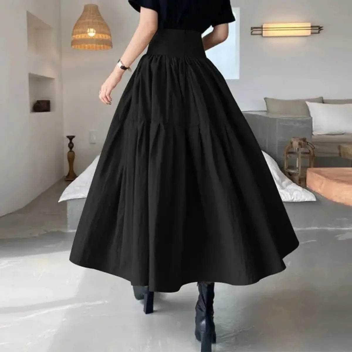 Woman wearing high-waisted pleated tiered midi skirt with black top.