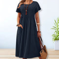 Woman wearing a mid-length relaxed day dress with short sleeves and pockets.
