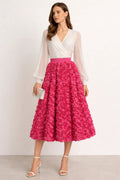 Woman wearing a midi skirt with rose appliques and a white blouse.