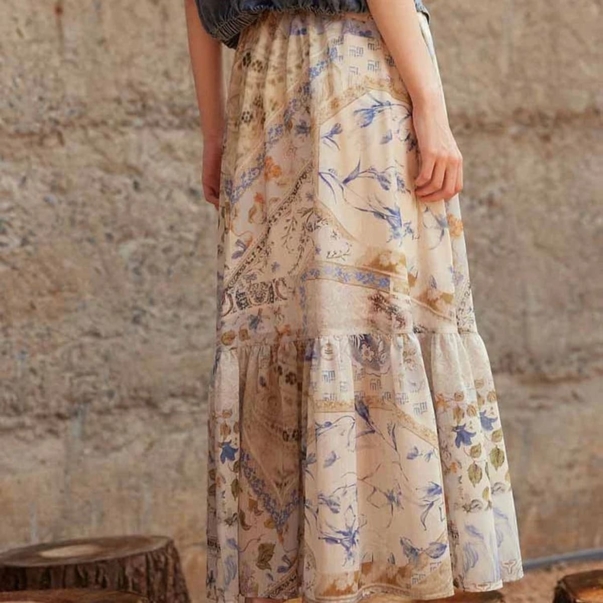 Cream-colored tiered maxi skirt with bohemian print and smocked waist.