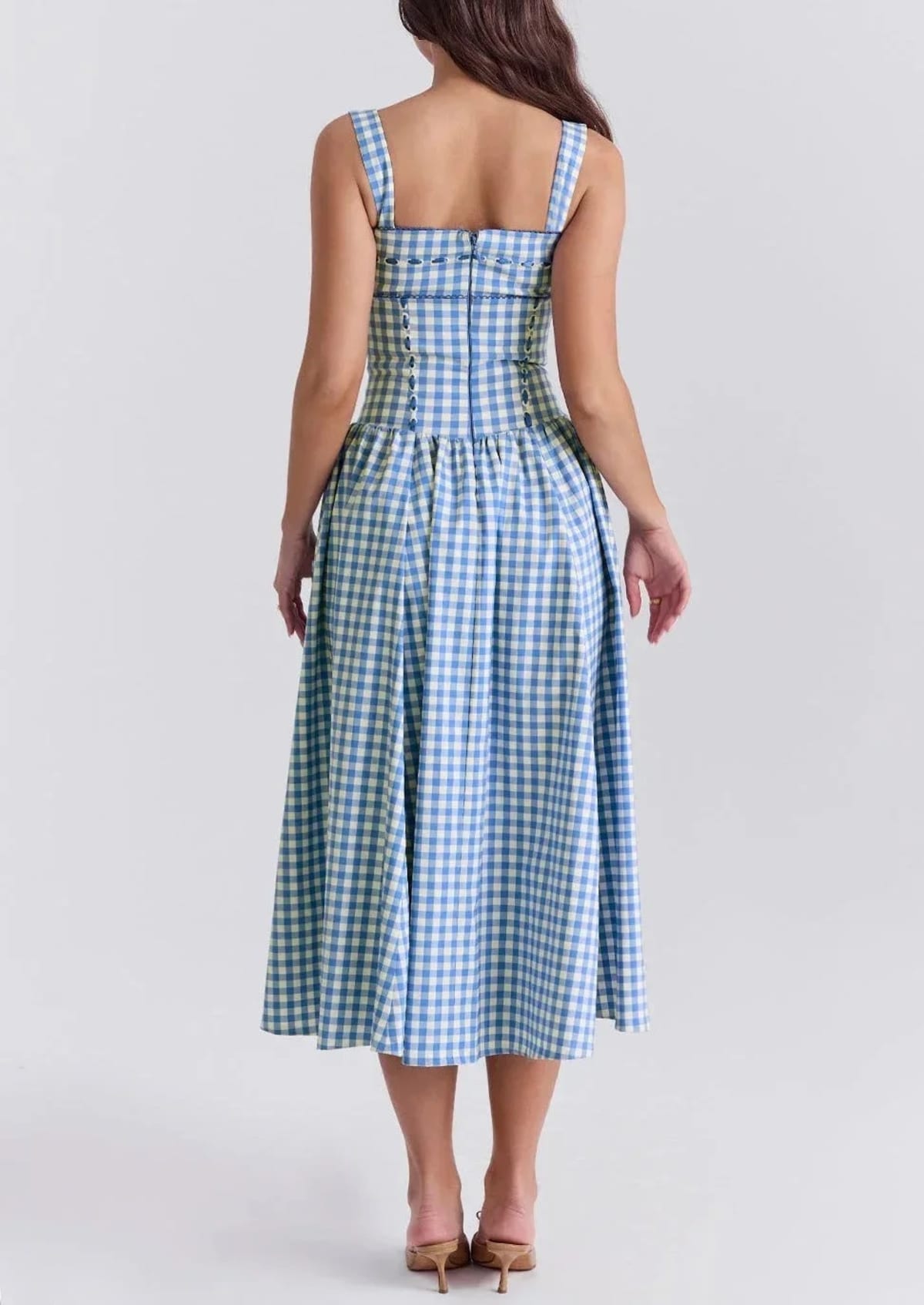 Woman wearing a gingham strapless midi dress on a dock by a lake.