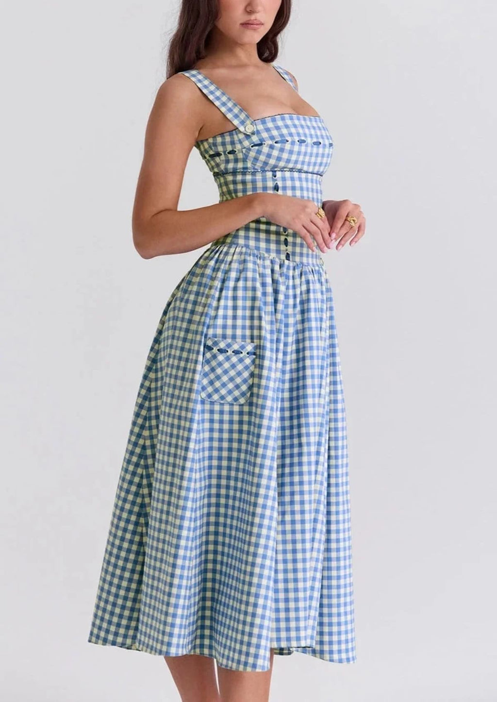 Woman wearing a gingham strapless midi dress on a dock by a lake.