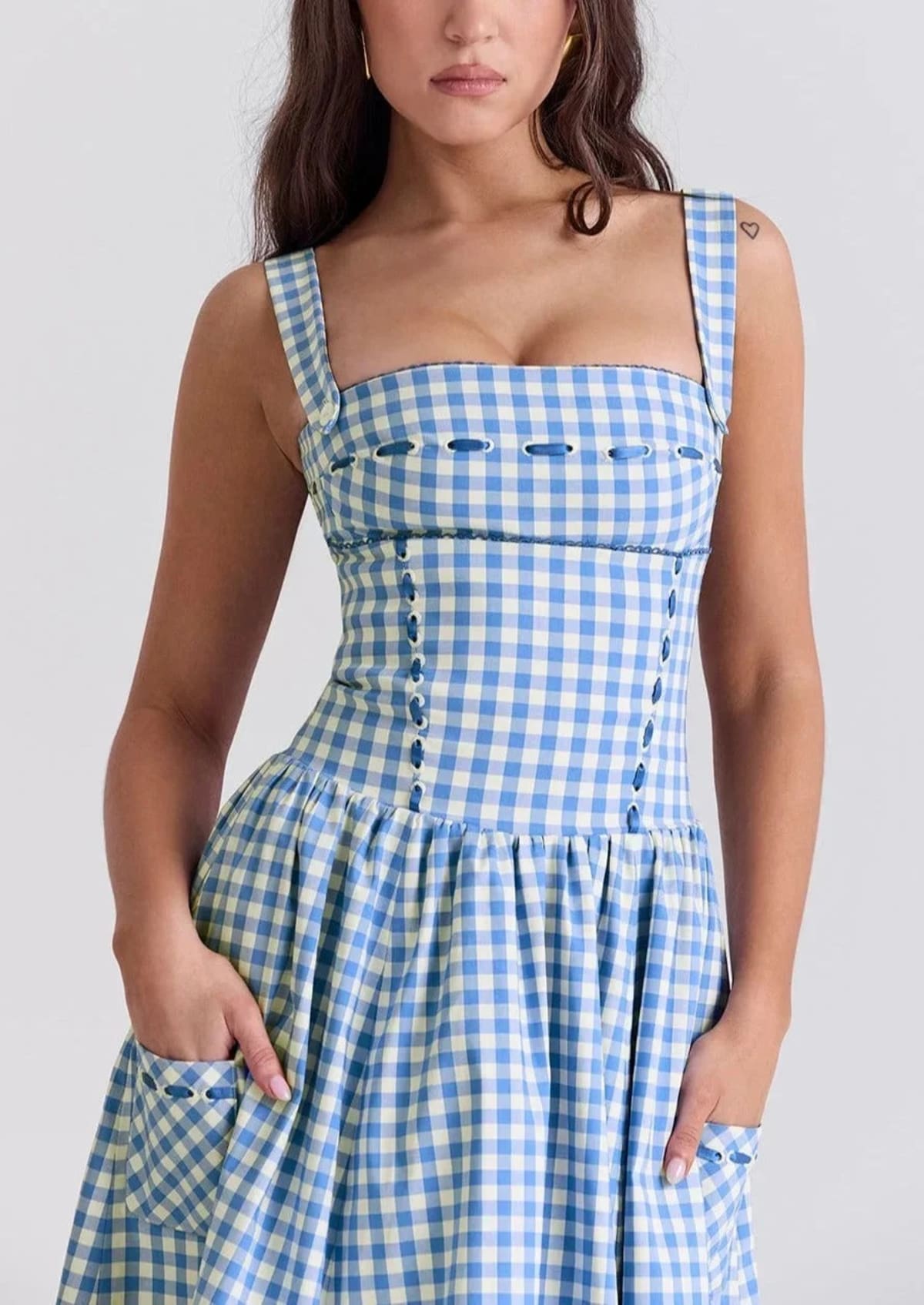 Woman wearing a gingham strapless midi dress on a dock by a lake.
