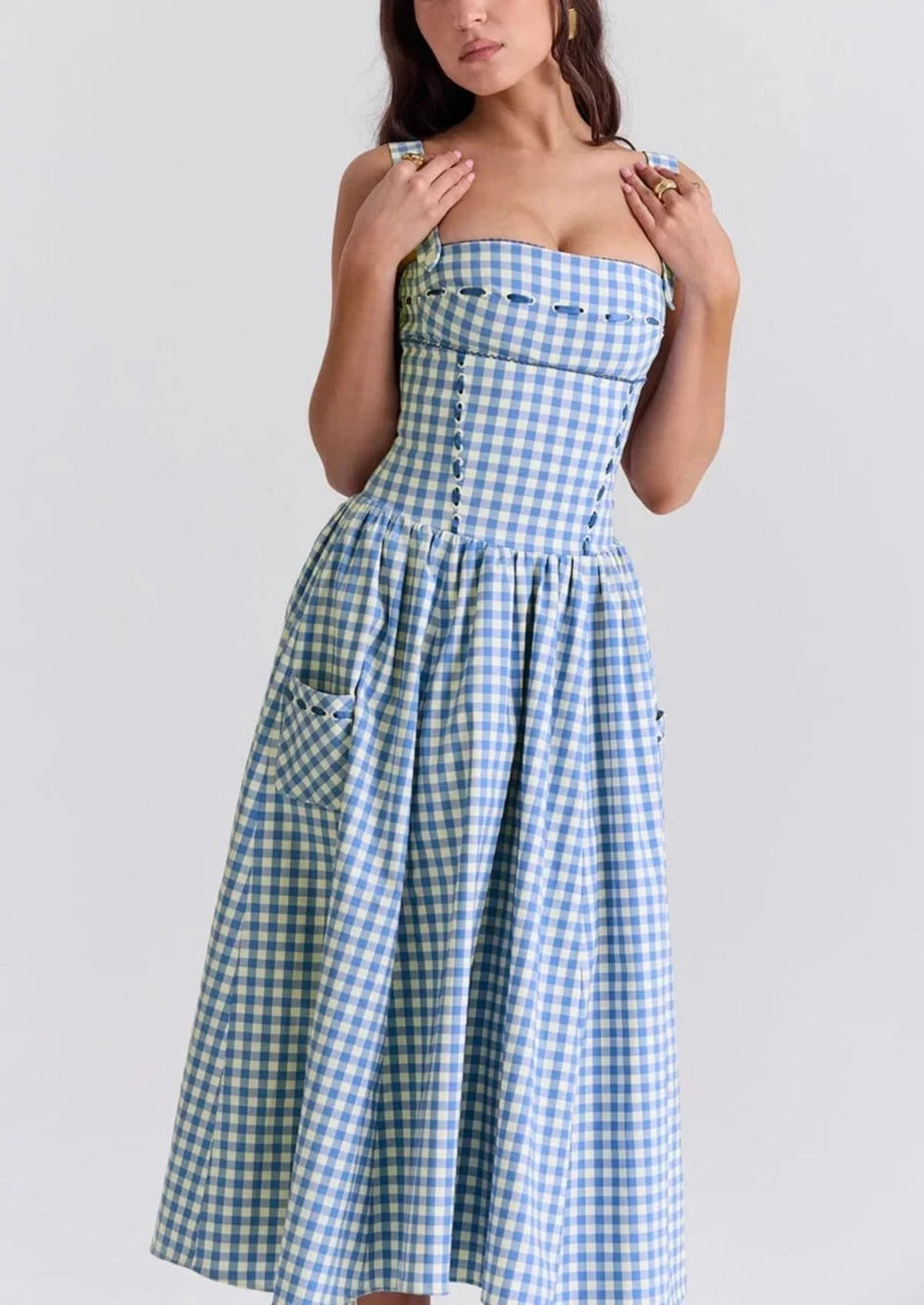Woman wearing a gingham strapless midi dress on a dock by a lake.