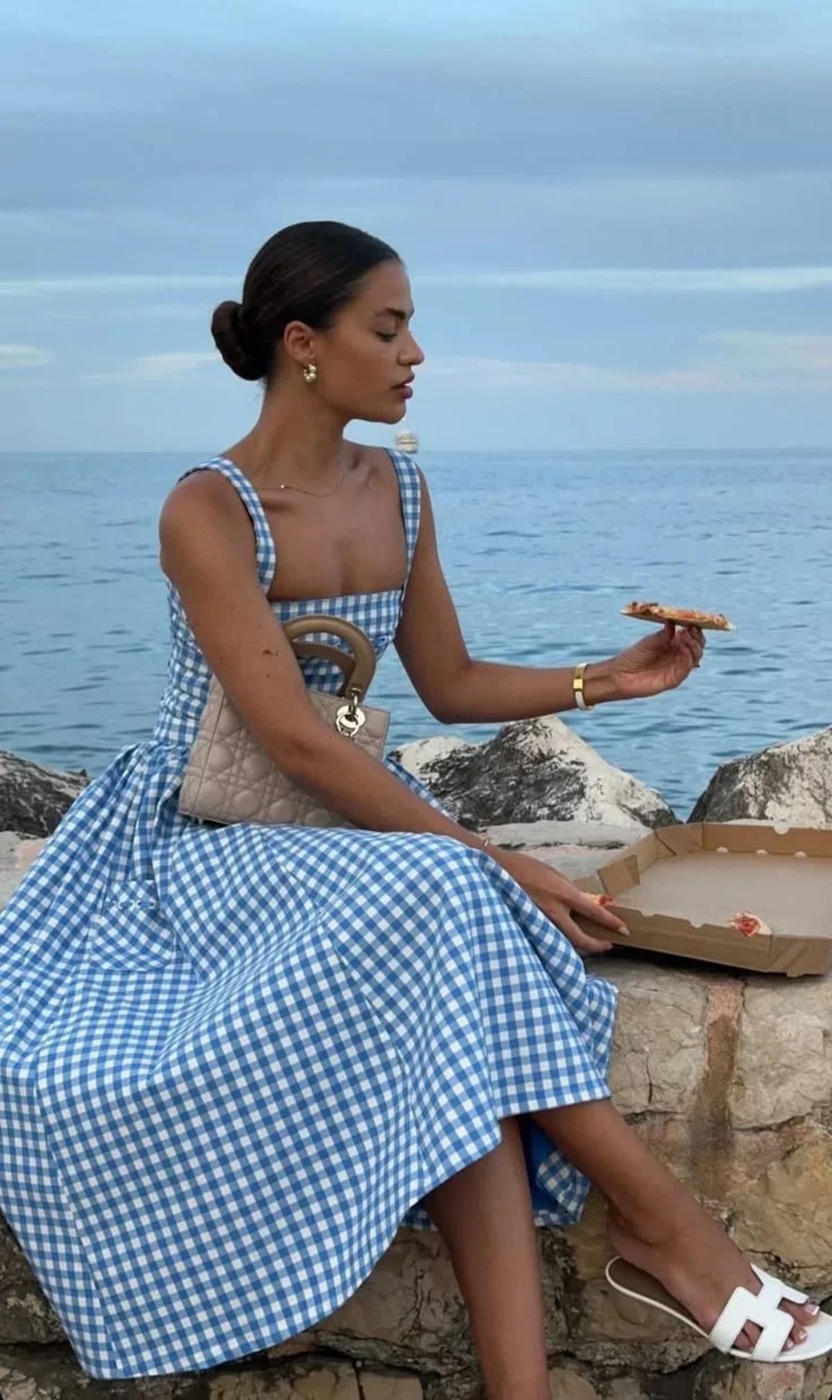 Woman wearing a gingham strapless midi dress on a dock by a lake.