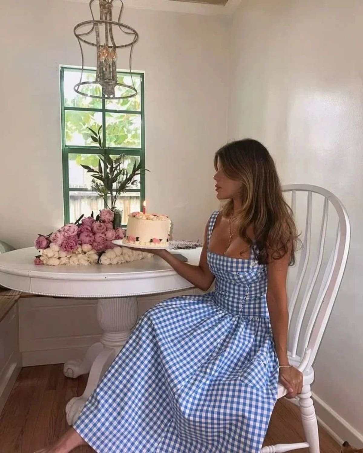 Woman wearing a gingham strapless midi dress on a dock by a lake.