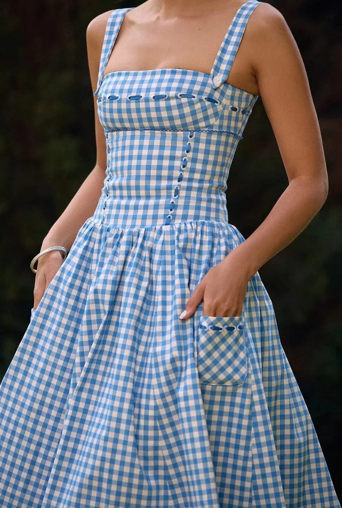 Woman wearing a gingham strapless midi dress on a dock by a lake.