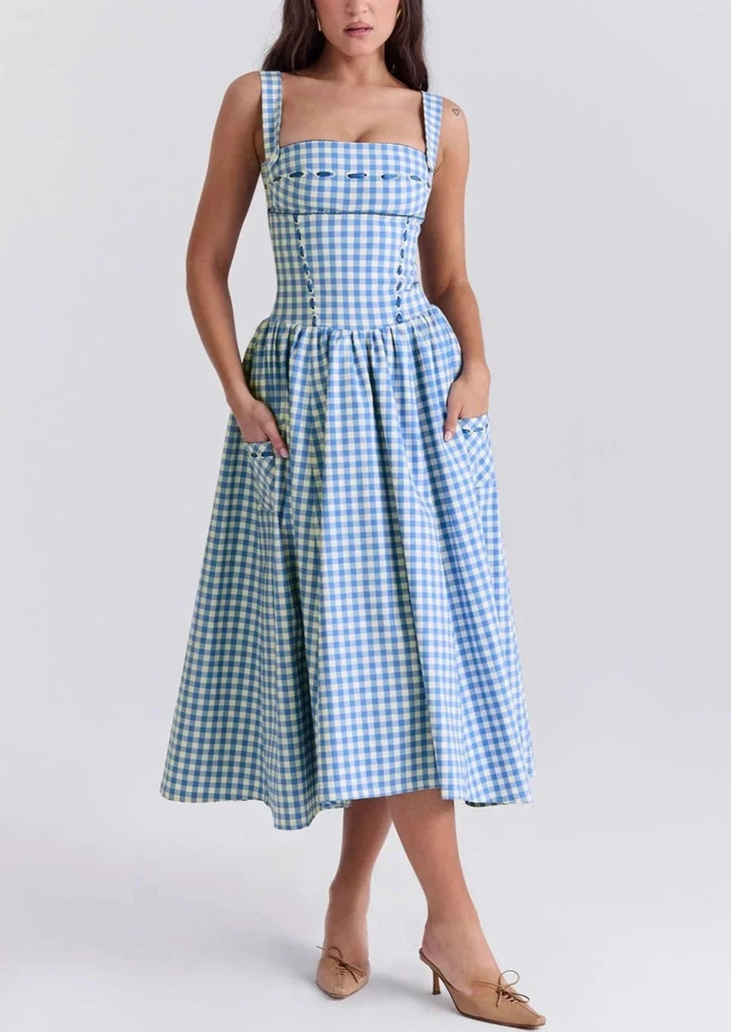 Woman wearing a gingham strapless midi dress on a dock by a lake.