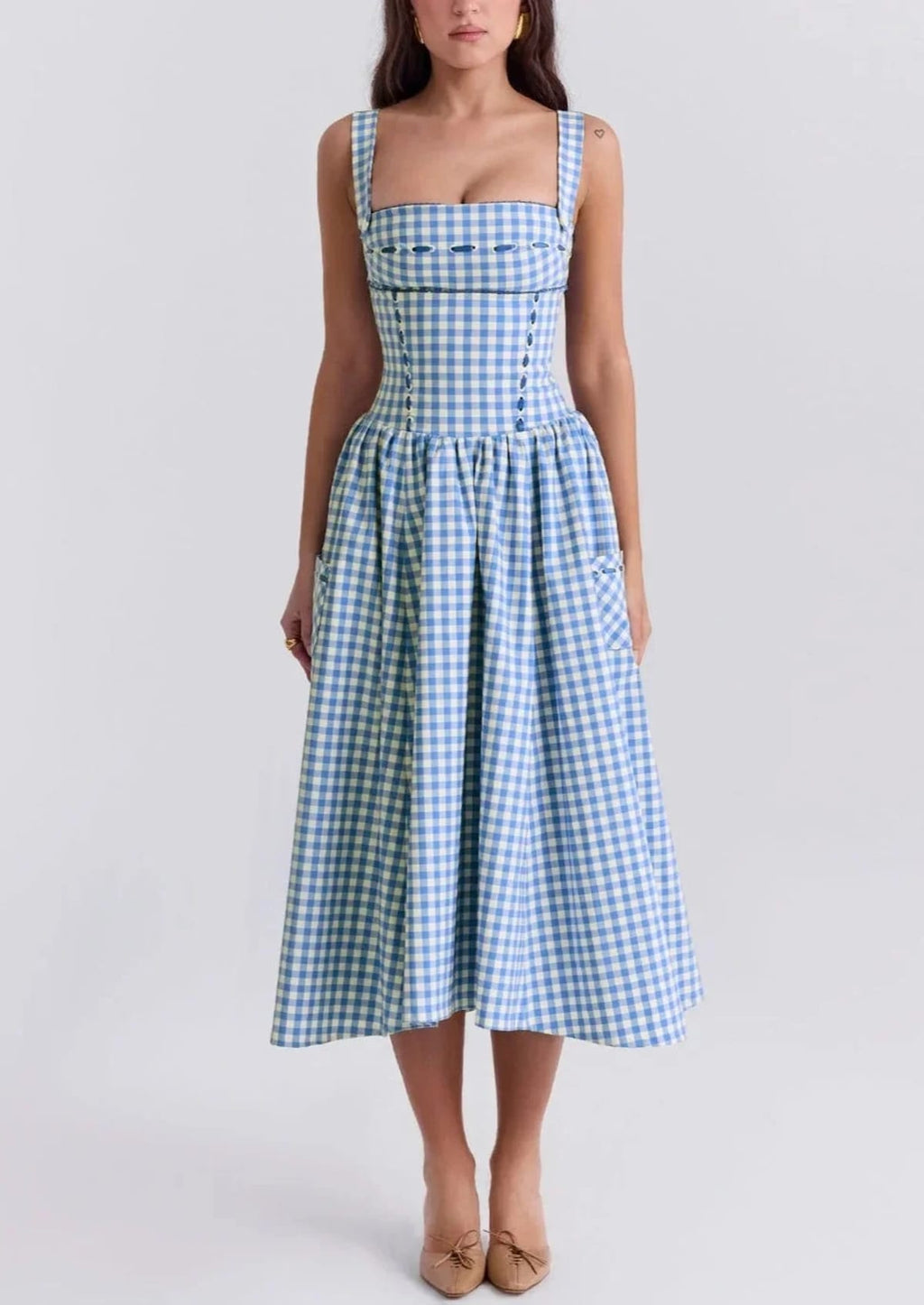 Woman wearing a gingham strapless midi dress on a dock by a lake.