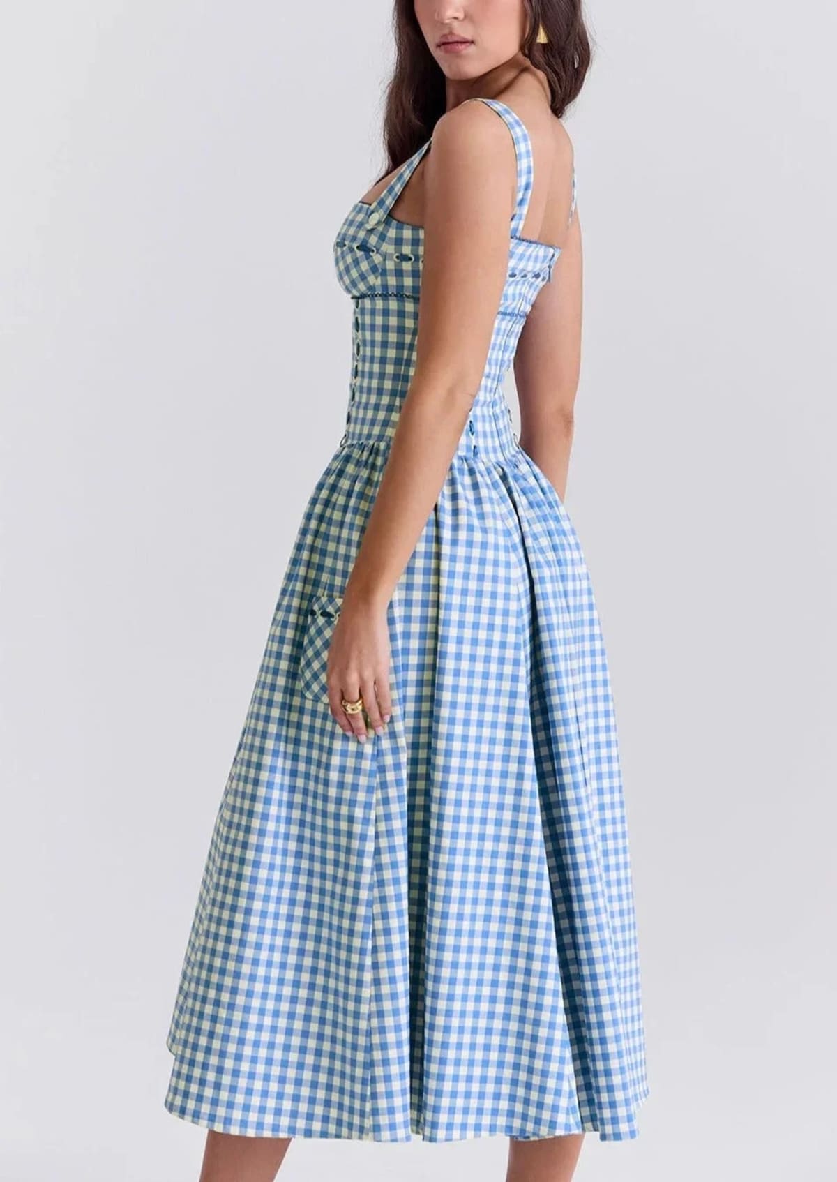Woman wearing a gingham strapless midi dress on a dock by a lake.
