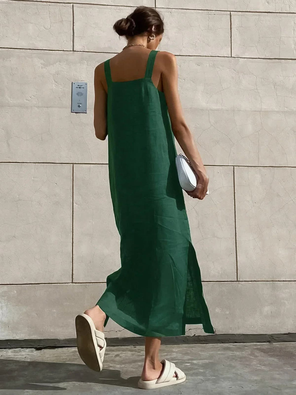 Woman in square neck midi dress with side slit against tiled wall.