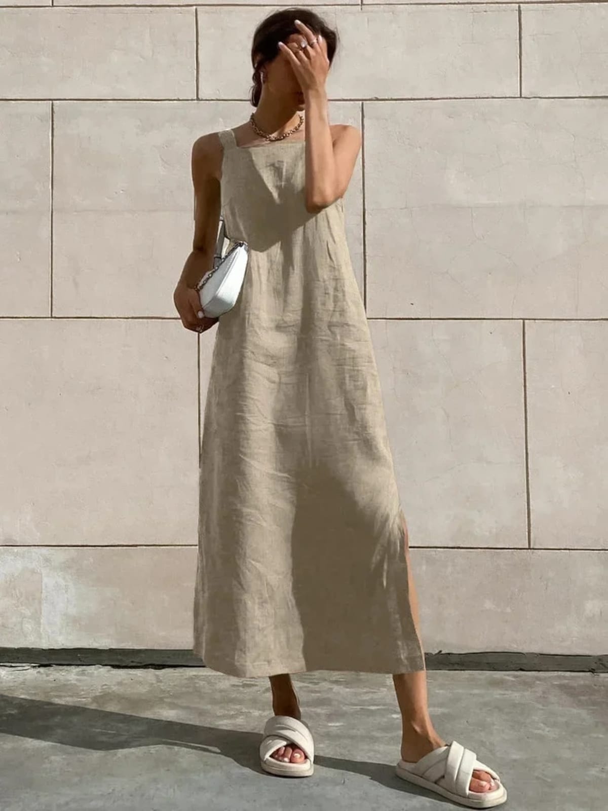 Woman in square neck midi dress with side slit against tiled wall.