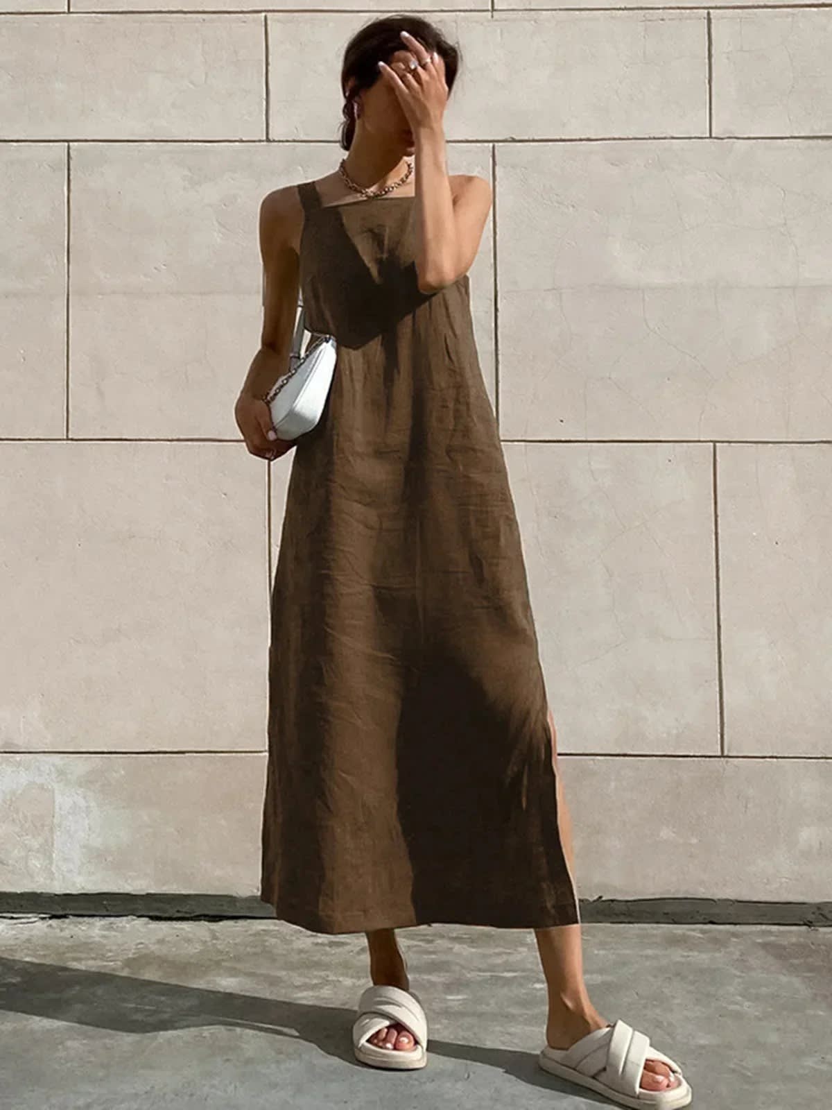 Woman in square neck midi dress with side slit against tiled wall.