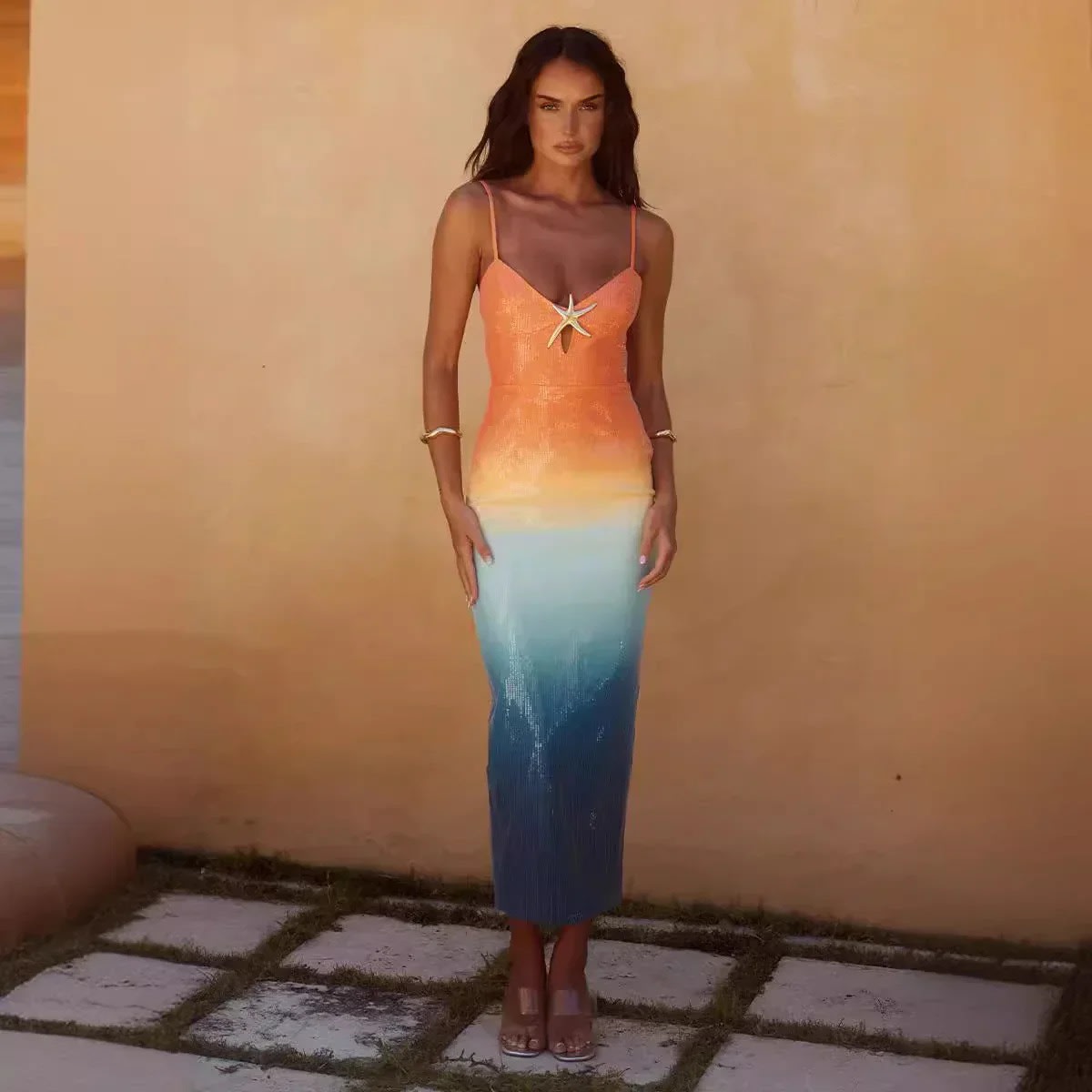 Woman wearing a strappy ombre sequin maxi dress with a starfish detail.