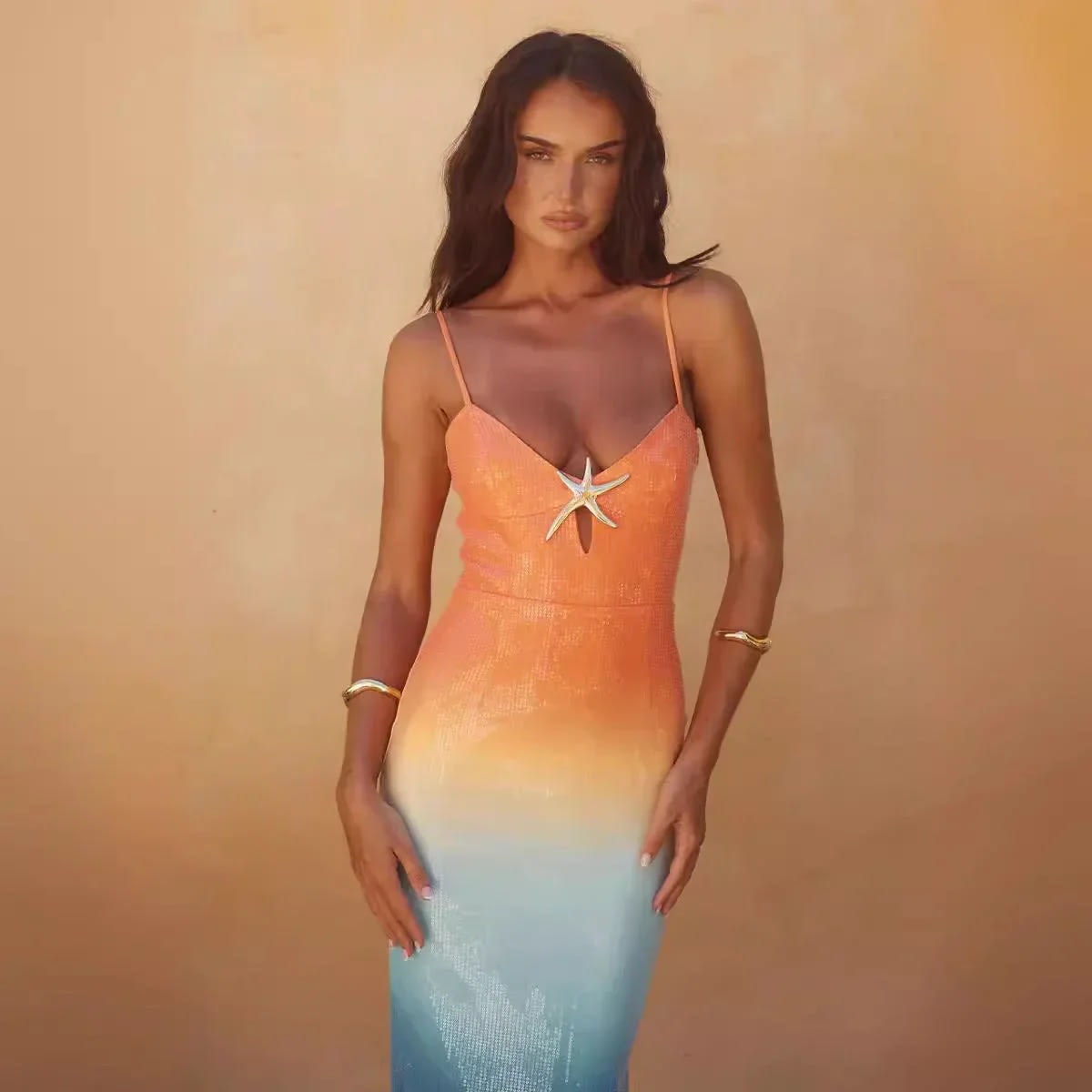 Woman wearing a strappy ombre sequin maxi dress with a starfish detail.