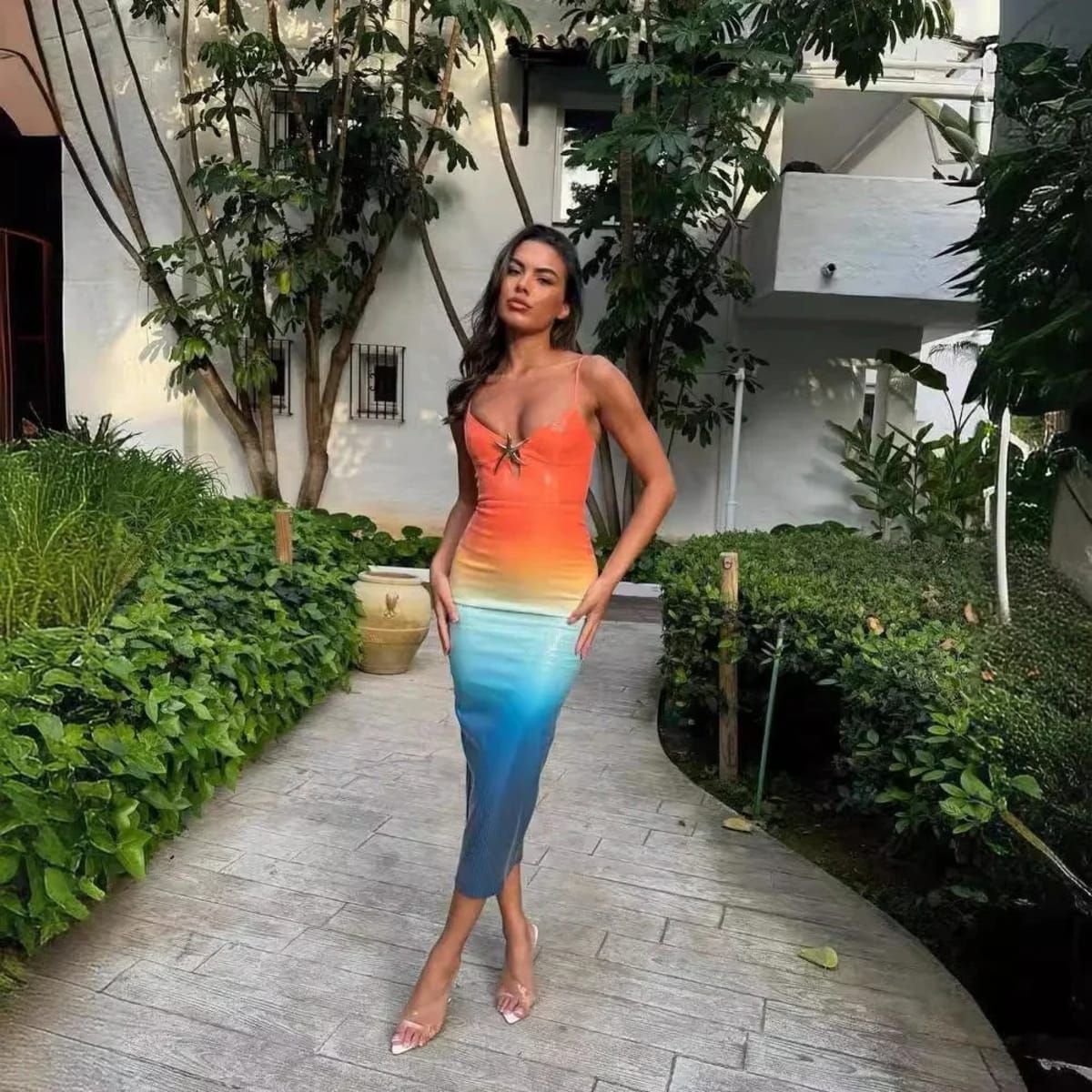 Woman wearing a strappy ombre sequin maxi dress with a starfish detail.