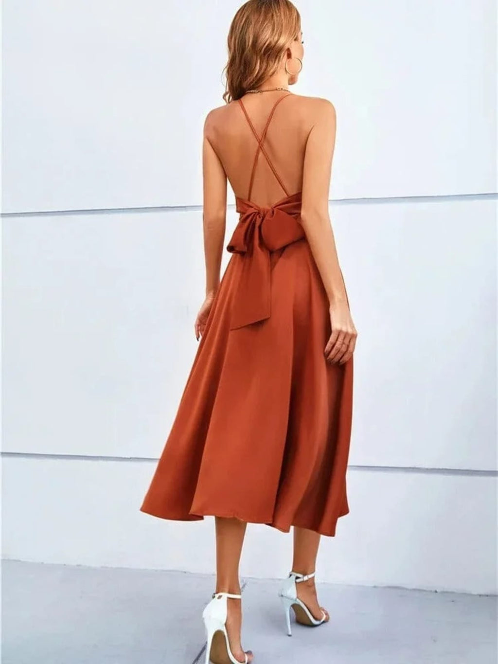 Woman in satin-finish wrap midi dress with spaghetti straps.