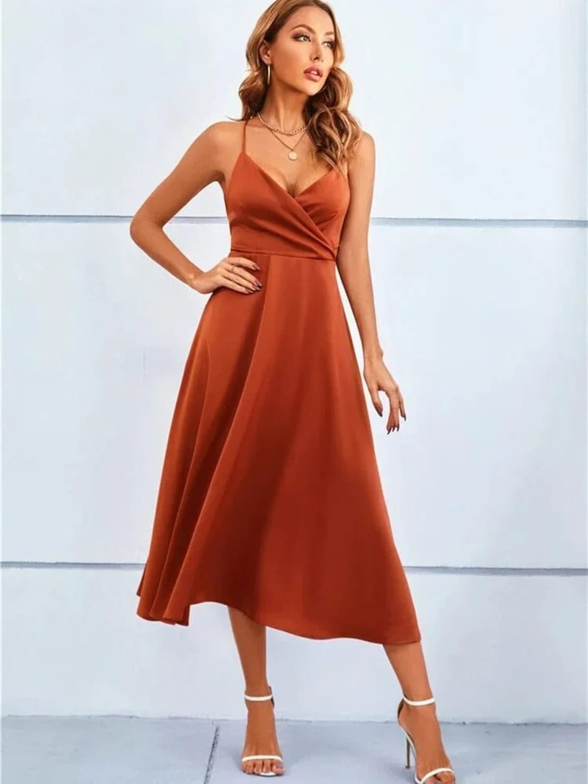 Woman in satin-finish wrap midi dress with spaghetti straps.