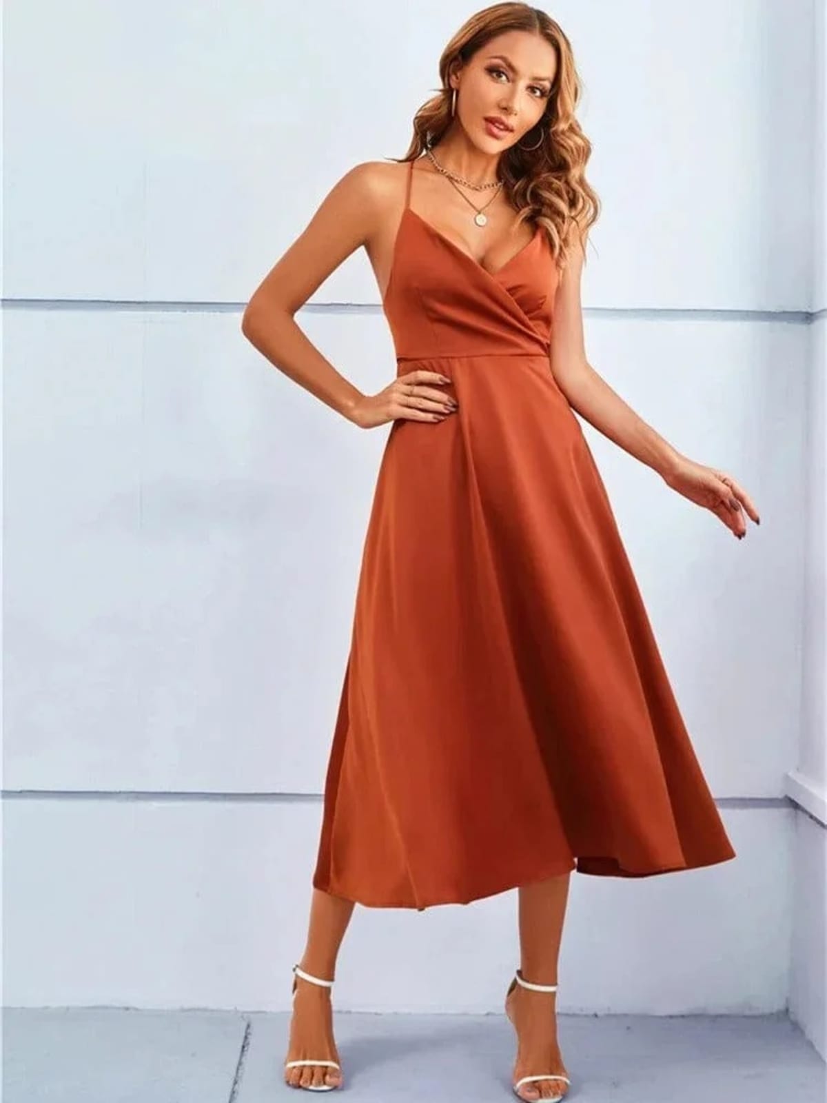 Woman in satin-finish wrap midi dress with spaghetti straps.