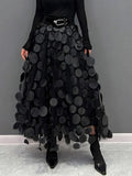 Person wearing a long maxi skirt with black round appliques on mesh.