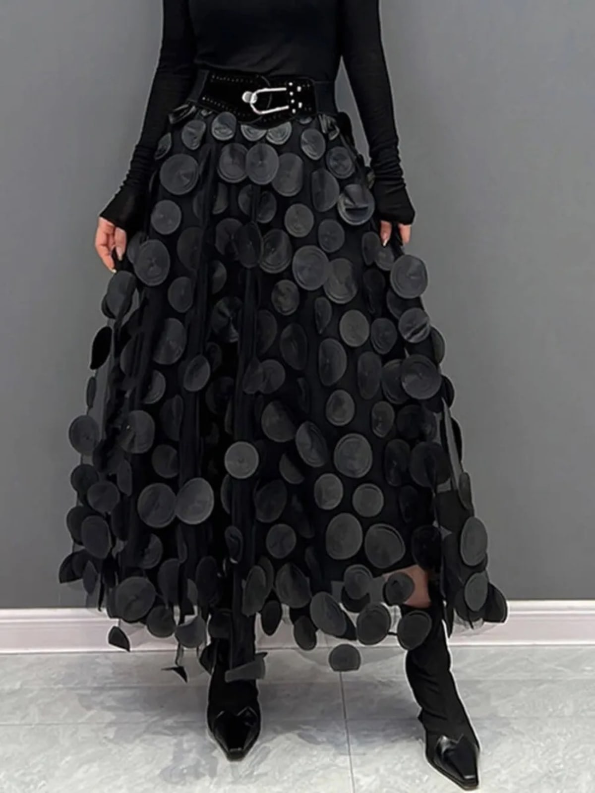 Person wearing a long maxi skirt with black round appliques on mesh.