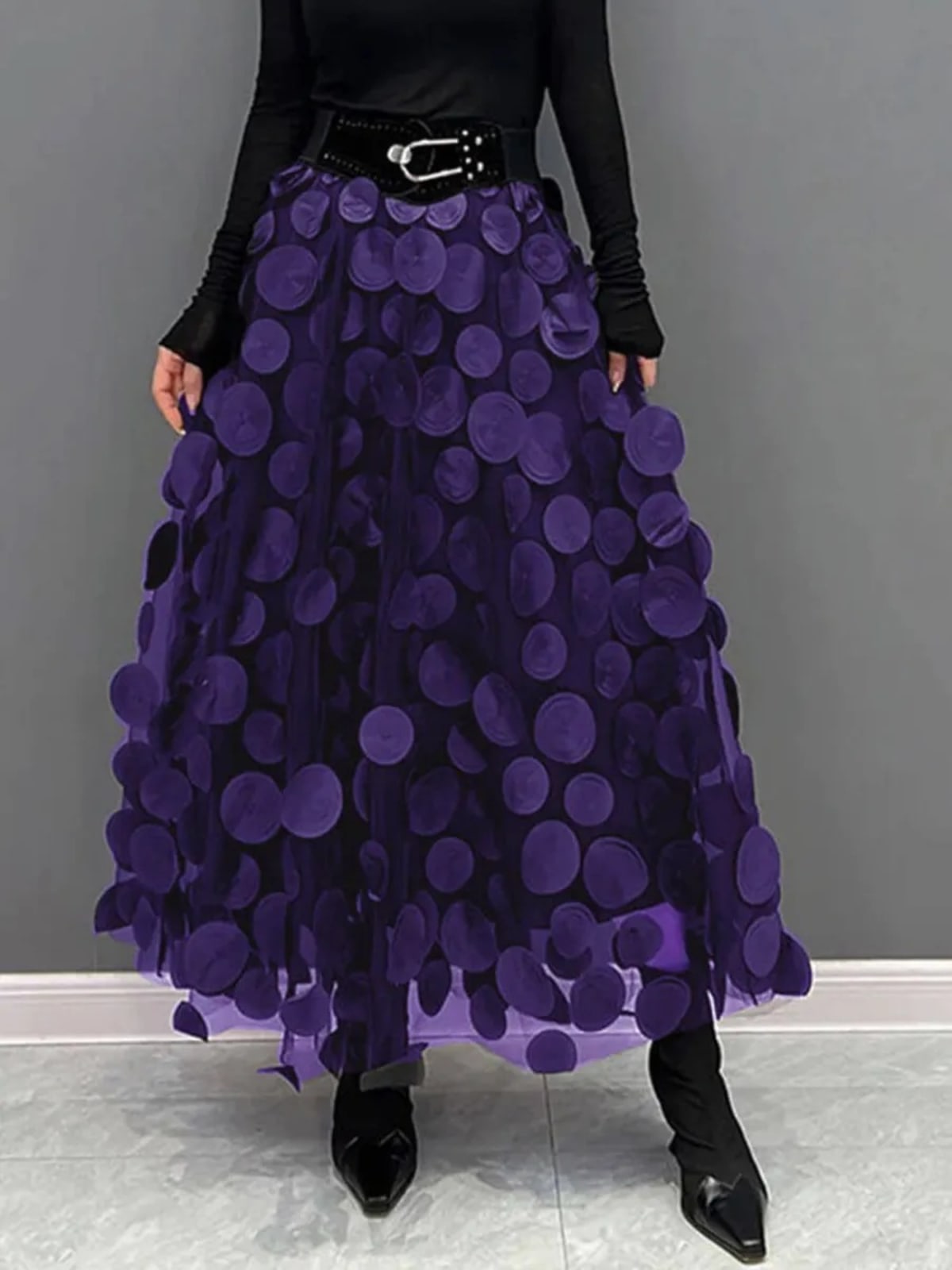 Person wearing a long maxi skirt with black round appliques on mesh.