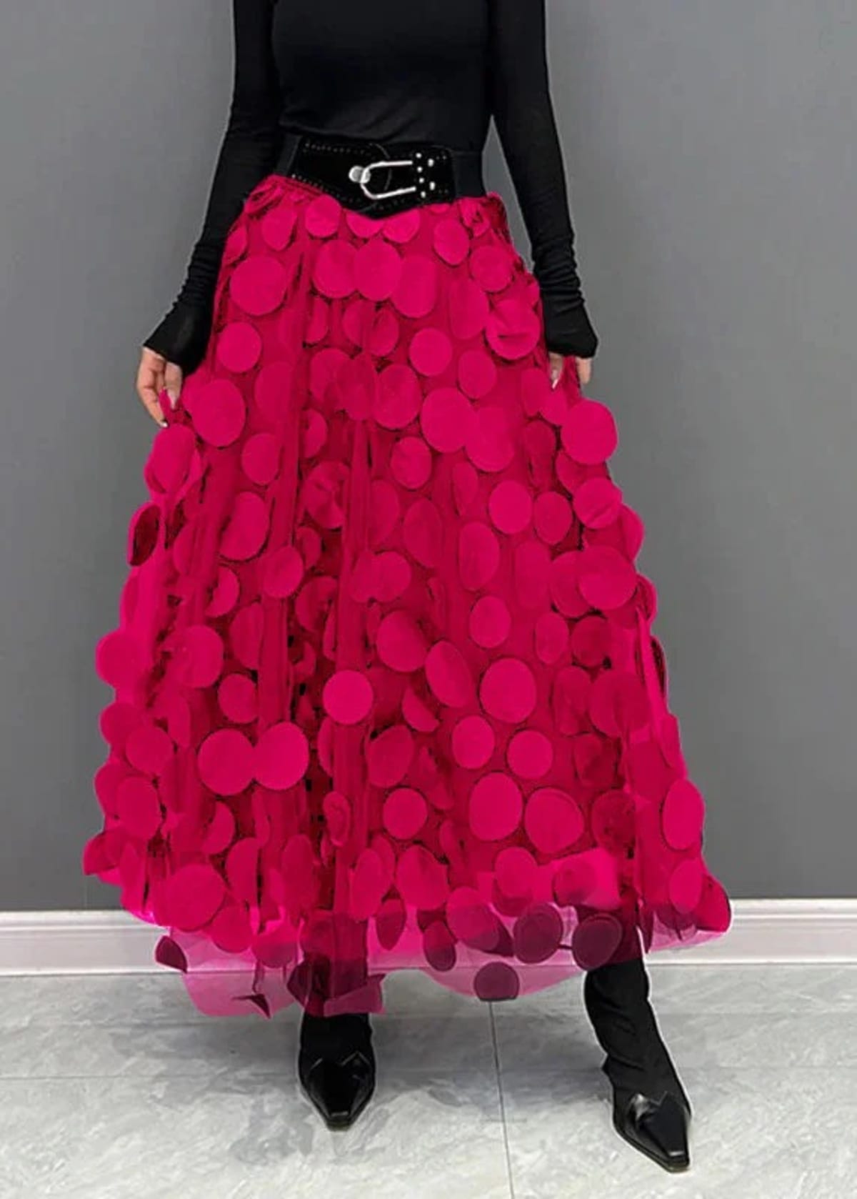 Person wearing a long maxi skirt with black round appliques on mesh.