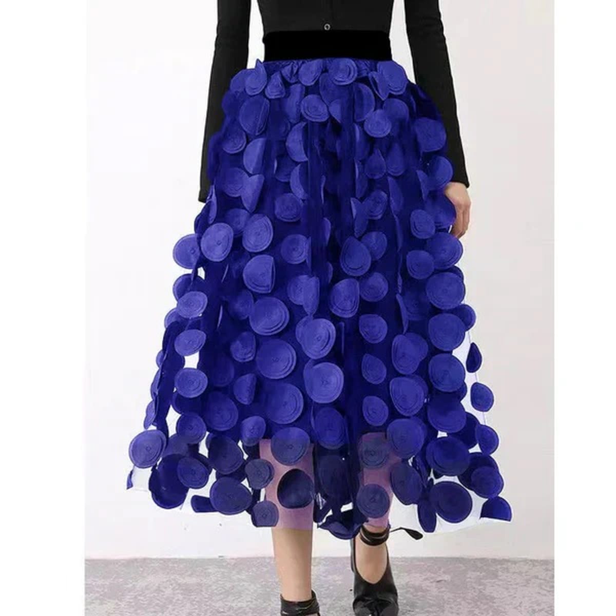 Person wearing a long maxi skirt with black round appliques on mesh.