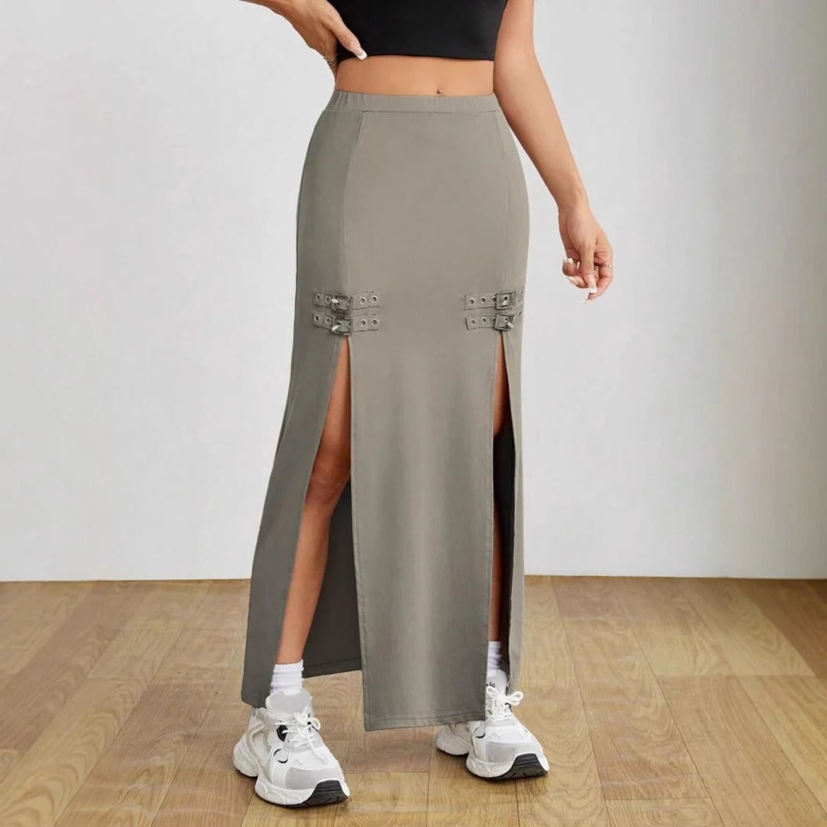 Woman wearing high-waisted maxi skirt with slits and buckle details.